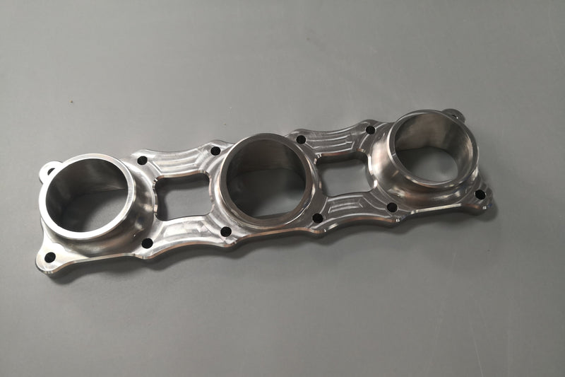 Precision CNC machined exhaust flange designed to transition smoothly from engine port to header runners