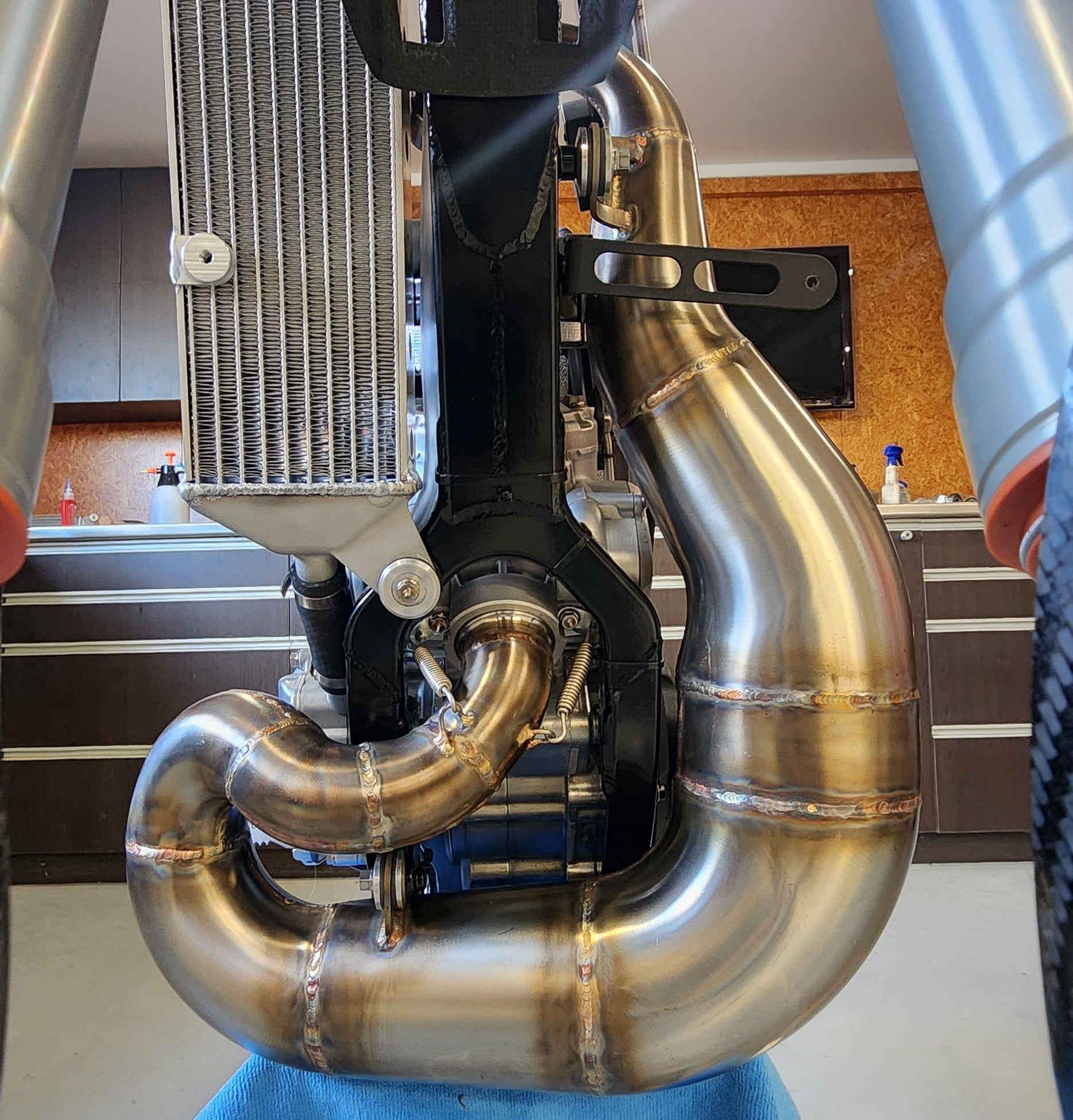 Custom stainless steel expansion chamber mounted on a purpose built FMX motorcycle with centralised exhaust routing