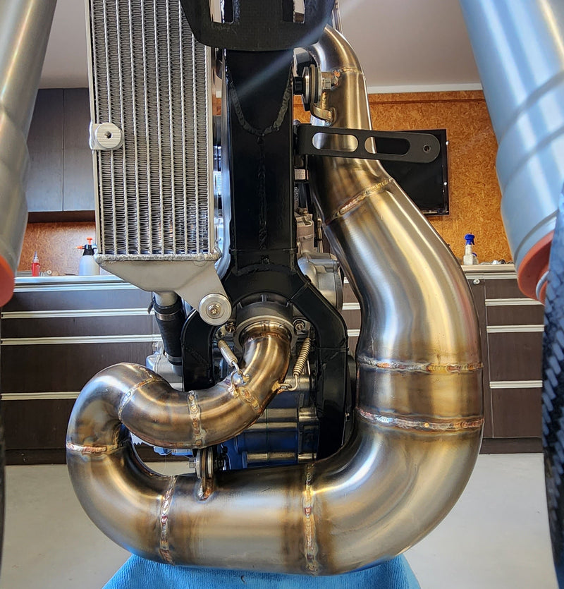 Custom stainless steel expansion chamber mounted on a purpose built FMX motorcycle with centralised exhaust routing
