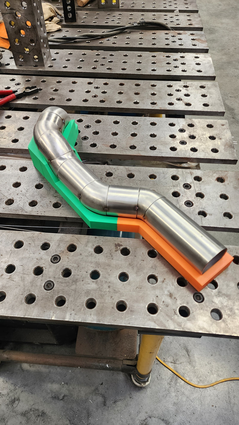 Exhaust manifold runners aligned in a custom 3D printed jig ensuring precise positioning and equal length during fabrication