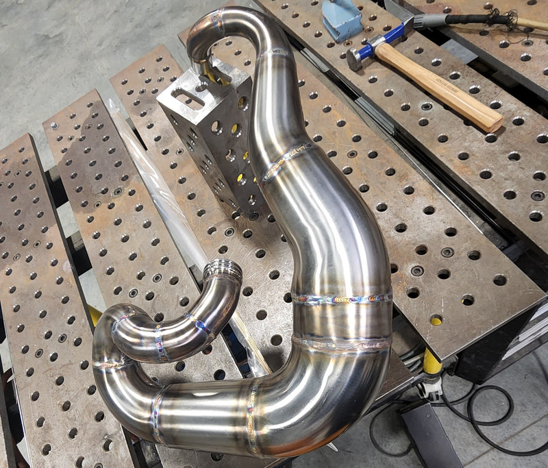 Stainless steel expansion chamber being hand welded for a custom FMX motorcycle exhaust system