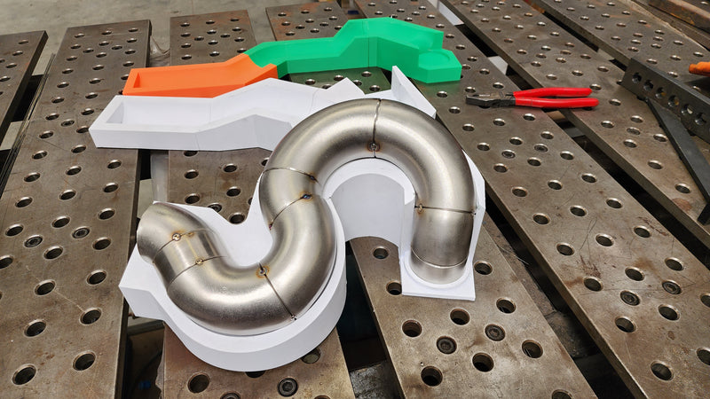 Exhaust runner positioned and tacked within a custom 3D printed alignment tool to maintain precise fitment and consistency