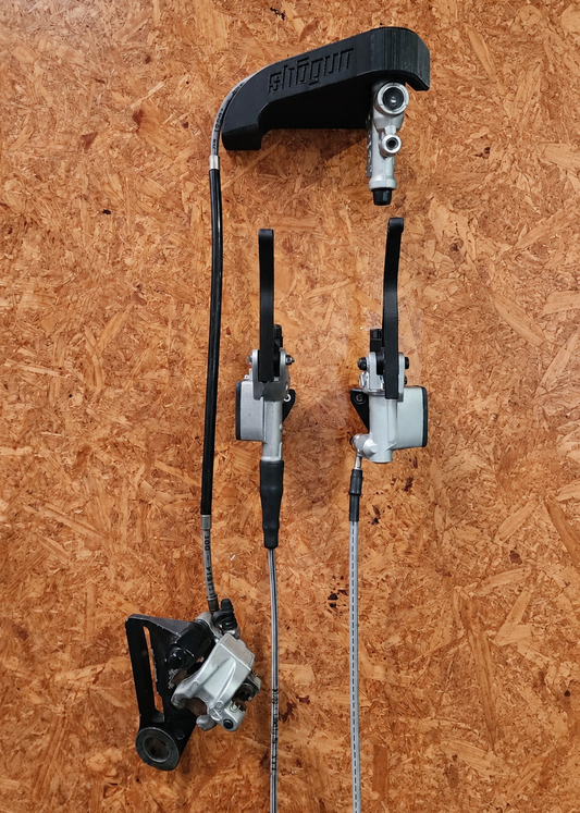 3D printed motorcycle front brake, clutch and rear brake wall hangers holding hydraulic assemblies on a workshop wall